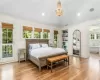 Bedroom with a notable chandelier, wood-type flooring, vaulted ceiling, access to outside, and ornamental molding