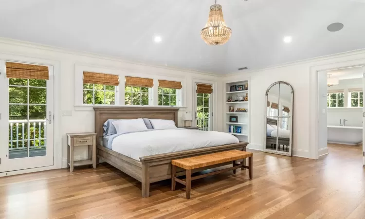 Bedroom with a notable chandelier, wood-type flooring, vaulted ceiling, access to outside, and ornamental molding