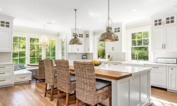 Kitchen featuring decorative backsplash, light hardwood / wood-style floors, white cabinetry, and sink