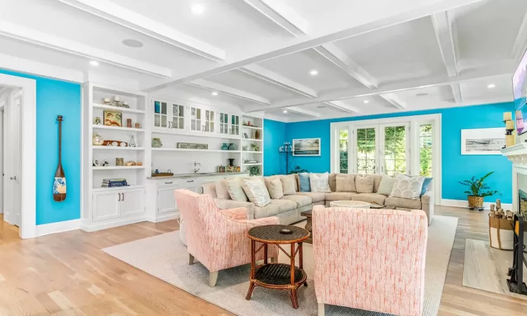 Living room featuring a fireplace, beam ceiling, light wood-type flooring, and coffered ceiling