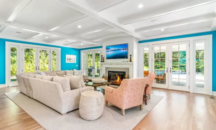 Living room featuring beam ceiling, light wood-type flooring, and french doors