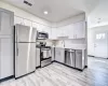 Kitchen featuring gray cabinetry, sink, light wood-type flooring, and appliances with stainless steel finishes