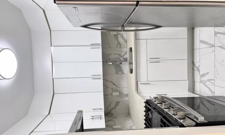 Kitchen featuring stainless steel fridge, stove, white cabinetry, and sink