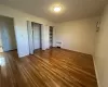 bedroom bedroom with a wall mounted AC, dark hardwood / wood-style flooring, radiator, and two closets