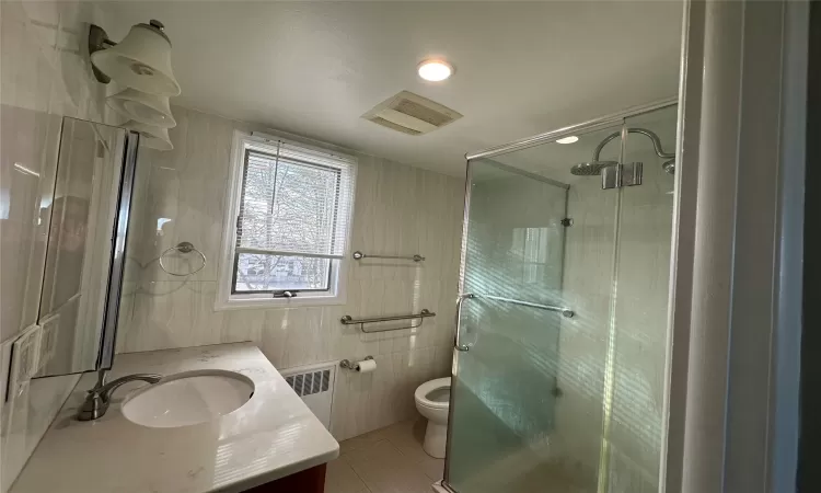 Downstairs Bathroom featuring an enclosed shower, radiator heating unit, vanity, and tile walls