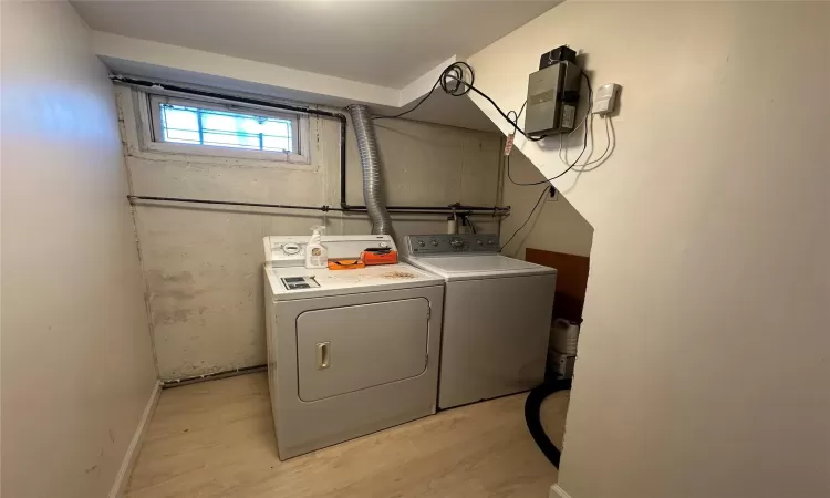 Clothes washing area with washer and dryer and light wood-type flooring