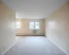 Carpeted spare room with a wall unit AC and baseboard heating