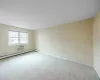 Carpeted spare room featuring a wall unit AC and a baseboard radiator