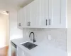 Kitchen with white cabinetry, sink, stainless steel dishwasher, light hardwood / wood-style floors, and decorative backsplash