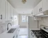 Kitchen with sink, stainless steel gas stove, light hardwood / wood-style flooring, a baseboard heating unit, and white cabinets