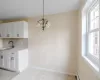 Kitchen with sink, tasteful backsplash, a baseboard heating unit, pendant lighting, and white cabinets