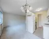 Kitchen with white cabinetry, sink, baseboard heating, white refrigerator, and decorative light fixtures