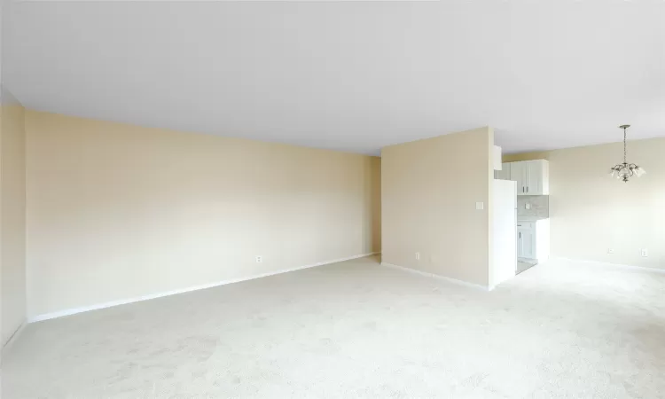 Spare room featuring light carpet and a notable chandelier