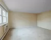 Unfurnished room with an AC wall unit, light carpet, and a baseboard heating unit