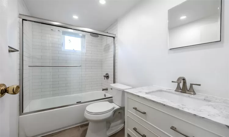 Full bathroom featuring shower / bath combination with glass door, vanity, and toilet