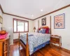 Bedroom with dark hardwood / wood-style flooring, a baseboard radiator, and crown molding