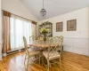 Dining area with a baseboard heating unit, a notable chandelier, lofted ceiling, and hardwood / wood-style flooring