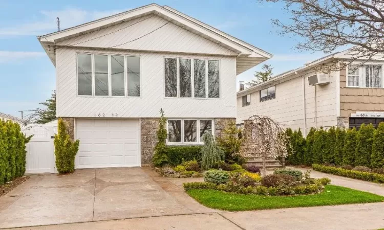 View of front of home featuring a garage and a wall unit AC