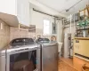 Laundry area featuring cabinets, water heater, washer and clothes dryer, light tile patterned flooring, and tile walls