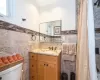 Bathroom featuring vanity, toilet, and tile walls