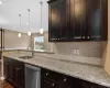 Kitchen with backsplash, light stone countertops, stainless steel appliances, and dark hardwood / wood-style floors