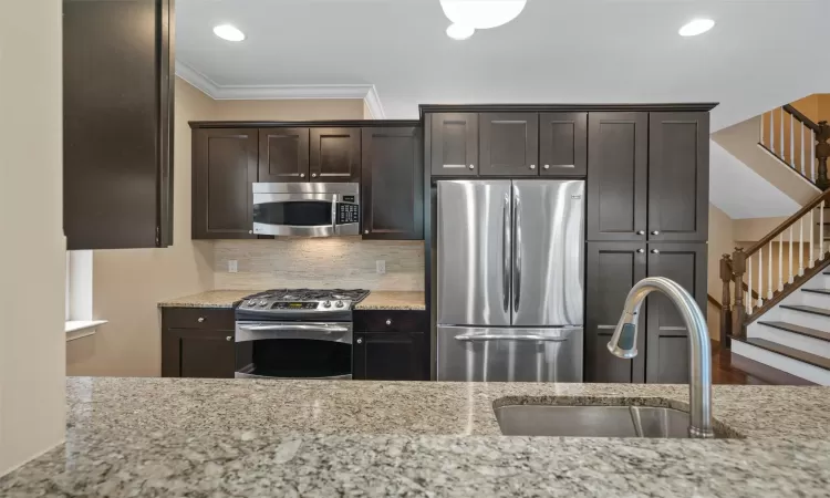 Kitchen with dishwasher, light stone counters, dark wood-type flooring, and sink