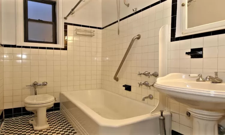 Bathroom featuring tile patterned floors, tiled shower / bath, tile walls, and toilet