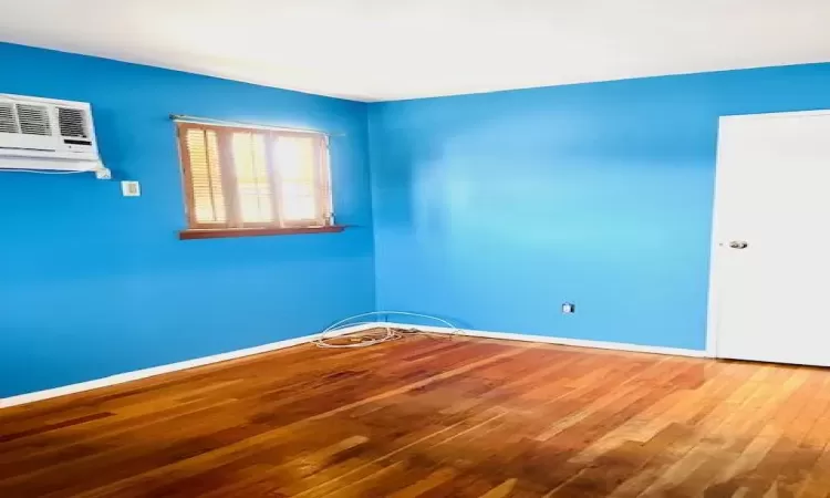 Bedroom featuring an AC wall unit and wood flooring