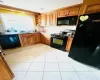 Kitchen featuring light tile patterned floors, sink, tasteful backsplash, and black appliances