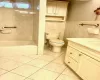 Full bathroom with vanity, tiled shower / bath combo, tile walls, and toilet