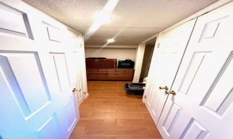 Corridor featuring light wood-type flooring and a textured ceiling