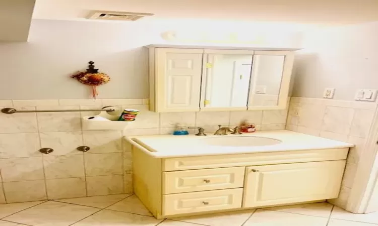 Bathroom featuring tile patterned floors, vanity, and tile walls