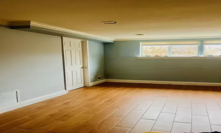 Empty room featuring wood-type flooring and crown molding