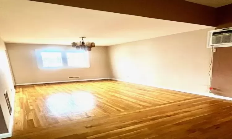 Dining area featuring hardwood  flooring, a wall mounted air conditioner, and an inviting chandelier