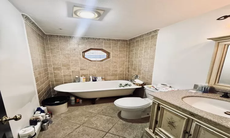 Bathroom with a bathing tub, vanity, toilet, and tile walls