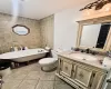 Bathroom featuring vanity, a bath, tile walls, and toilet