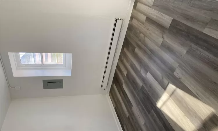 Empty room featuring dark hardwood / wood-style flooring, baseboard heating, and electric panel