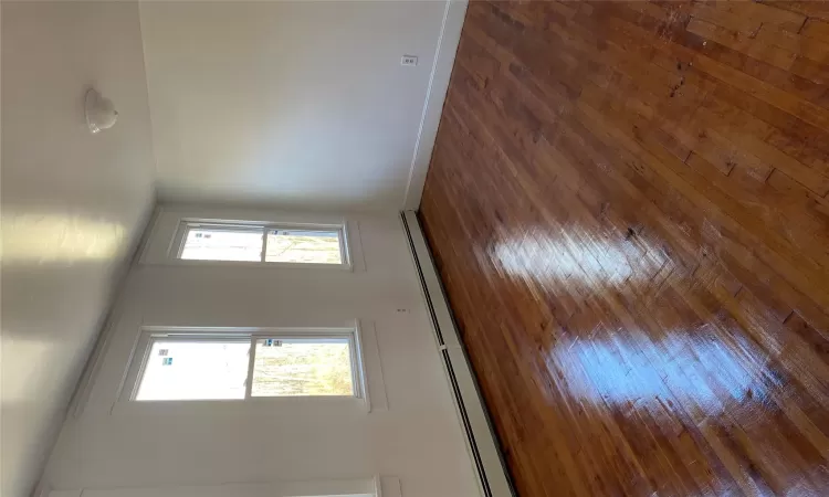 Unfurnished room featuring dark hardwood / wood-style floors and baseboard heating