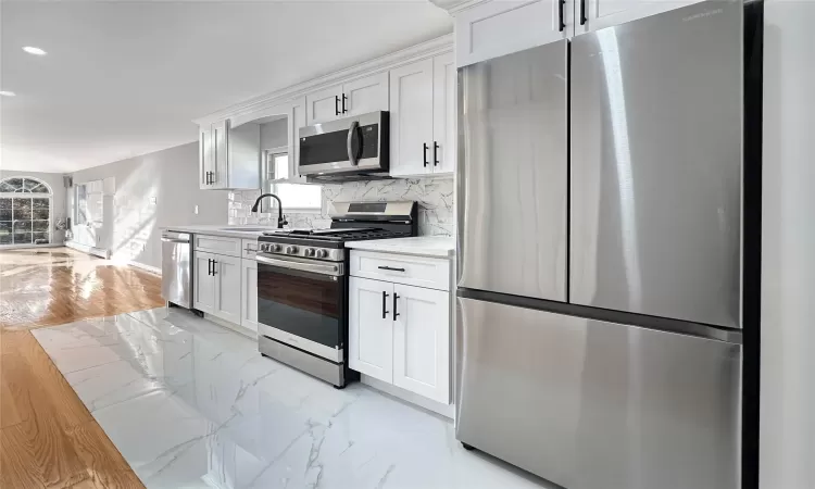 Kitchen with plenty of natural light, sink, white cabinetry, and stainless steel appliances