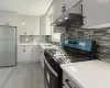 Kitchen featuring backsplash, stainless steel appliances, sink, light hardwood / wood-style floors, and range hood