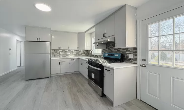 Kitchen with white cabinets, light wood-type flooring, sink, and appliances with stainless steel finishes