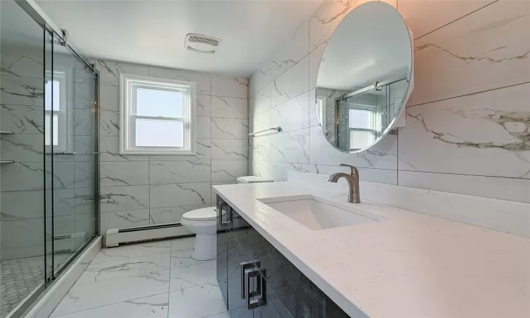 Bathroom with baseboard heating, an enclosed shower, toilet, vanity, and tile walls