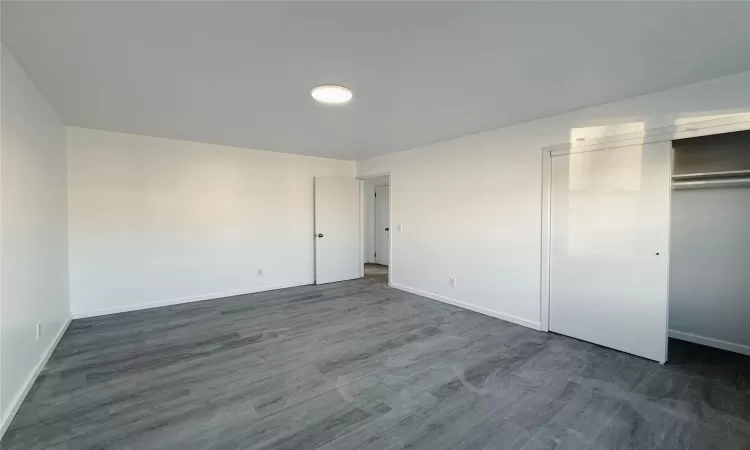 Unfurnished bedroom with dark hardwood / wood-style flooring and a closet