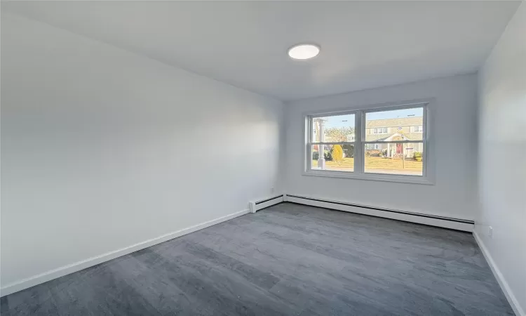 Carpeted empty room featuring baseboard heating