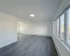 Empty room featuring a baseboard radiator, a healthy amount of sunlight, and dark hardwood / wood-style floors