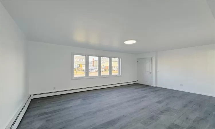 Empty room featuring baseboard heating and dark hardwood / wood-style flooring