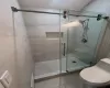 Bathroom featuring tile patterned flooring, a shower with door, and toilet