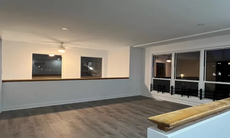 Primary bedroom / loft with ceiling fan and dark hardwood / wood-style floors