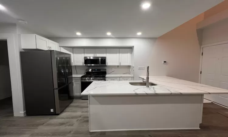 Kitchen featuring light stone countertops, stainless steel appliances, sink, light hardwood / wood-style flooring, and white cabinets