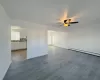 Empty room featuring hardwood / wood-style flooring, baseboard heating, and ceiling fan